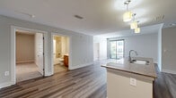 This thoughtfully designed 2-bedroom, 2-bathroom residence in Austin, TX offers a functional and modern single-floor layout. The open-concept living and kitchen area serves as the heart of the home, featuring rich wood-tone cabinetry, a dark tile backsplash, stainless steel appliances, and a large granite-topped island with a double sink illuminated by stylish pendant lighting. The living room extends seamlessly from the kitchen, showcasing durable wood-look plank flooring and a sliding glass door that opens to a private balcony with views of the surrounding area.

Both bedrooms are carpeted and filled with natural light. The spacious primary bedroom features a large window with green tree views, while the secondary bedroom includes a ceiling fan and a tall narrow window. A dedicated closet with wire shelving provides ample storage.

The two bathrooms are finished with warm wood vanities, white countertops, and full tub-shower combinations. One bathroom features white subway tile surround with a curved shower rod, while the other offers a clean, neutral tile floor. Neutral gray tones throughout the living spaces create a calm, cohesive ambiance, making this residence a comfortable and practical home in Austin.