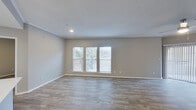 This single-floor residence offers a clean, modern aesthetic defined by consistent wood-look flooring and neutral gray tones throughout. The open living area is a standout feature, anchored by a classic fireplace and a ceiling fan overhead. An elegant arched doorway connects the living space to the entryway, where light tile flooring welcomes you in. Multiple windows fitted with white blinds allow natural light to fill the spacious living and dining areas, which also benefit from a sliding door providing additional outdoor access.

The kitchen is outfitted with white cabinetry, light stone countertops, a subway tile backsplash, and a full suite of stainless steel appliances, including a range, microwave, and refrigerator. Wood-look flooring continues seamlessly into the kitchen, reinforcing the cohesive design throughout.

The bedrooms are generously proportioned, each featuring wood-look floors, ceiling fans or recessed lighting, and windows that bring in natural light. The primary bathroom includes a soaking tub with a shower, and direct access to a spacious walk-in closet with built-in shelving. A second bathroom features grab bars and a tub, offering practical accessibility. Textured ceilings and crisp white trim complete the clean, move-in-ready presentation of this residence.