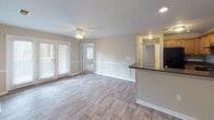 This single-story residence at Walden offers a thoughtfully designed layout with a cohesive neutral color palette throughout. The open-concept living and dining area serves as the centerpiece of the home, featuring wood-look flooring, a ceiling fan with integrated lighting, and recessed lighting. A peninsula countertop with dark granite-style surfaces connects the living space to the kitchen, allowing for an open flow between the two areas. French doors in the living room invite natural light and provide outdoor access.

The kitchen is well-appointed with warm honey-toned wood cabinetry, dark granite-style countertops, tile flooring, and black appliances including a range, refrigerator, and dishwasher. An overhead range hood and ample upper and lower cabinet storage add to its functionality.

The bedrooms are finished with plush carpeting and ceiling fans, offering a comfortable retreat. Multiple windows provide natural light and views of the surrounding area. Each bedroom includes closet access via classic six-panel doors.

The bathrooms feature soaking tubs with tiled surrounds in a neutral beige tone, chrome fixtures, and curved shower curtain rods, combining practicality with a clean, consistent aesthetic throughout the home.