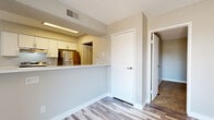 Located at 3800 W Chandler Blvd in Chandler, Arizona, this 1-bedroom, 2-bathroom unit offers a thoughtfully designed single-floor layout that maximizes every inch of its compact footprint. The open-concept living area features light-toned wood-look flooring that flows seamlessly throughout the main living spaces, creating a clean and cohesive aesthetic. A peninsula-style kitchen overlooks the living area, complete with white shaker cabinetry, light quartz-style countertops, stainless steel appliances including a refrigerator and range, and a built-in overhead light fixture that brightens the workspace. The galley-style kitchen interior provides ample cabinet storage and counter space. The bedroom offers plush wall-to-wall carpeting, neutral gray walls, and a window with vertical blinds that allows for natural light. A dedicated closet provides convenient storage. Both bathrooms are finished with wood-look vinyl flooring; one features a full tub-shower combo, while the other includes a modern gray vanity with white countertop and a framed mirror. A textured ceiling is consistent throughout the unit, and centralized HVAC venting ensures year-round comfort. The overall design is clean, neutral, and move-in ready.