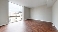 Located at 401 Granby St in the heart of Norfolk, VA, this two-bedroom, two-bathroom residence offers a well-designed single-floor layout with a clean, modern aesthetic. Rich, dark hardwood-style flooring runs throughout the entire unit, creating a warm and cohesive look from room to room. The open-concept living, dining, and kitchen area serves as the central hub of the home. The kitchen is outfitted with stainless steel appliances — including a refrigerator, electric range, and microwave — warm-toned wood cabinetry, gray countertops, a double-basin sink, and stylish pendant lighting that anchors the peninsula. Floor-to-ceiling windows in the living area flood the space with natural light and provide views of the surrounding Norfolk cityscape. Both bedrooms are generously proportioned with high ceilings, adding to the sense of openness. The primary bedroom features a large closet, while the second bedroom offers its own windowed wall for additional natural light. Four closets are distributed throughout, providing ample storage. The two bathrooms each feature white vanity cabinetry with gray countertops; one includes a shower-tub combination. A dedicated laundry area and utility room round out the functional layout of this well-appointed urban residence.