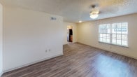 Located at 2080 Lobdell Blvd in Baton Rouge, Louisiana, this single-floor unit offers a well-designed layout with consistent wood-style flooring throughout. The open living and dining area is generously proportioned, bathed in natural light through blinded windows, and features ceiling fans and a textured ceiling. The space flows seamlessly toward the kitchen, which is visible from the living area and provides a practical, connected feel.

The galley-style kitchen is thoughtfully outfitted with warm honey-toned cabinetry, granite-look countertops, a stainless steel sink, and a full suite of black and stainless steel appliances including a refrigerator, range, microwave, and dishwasher. A centrally positioned window fills the kitchen with natural light.

The bedrooms continue the wood-style flooring and feature ceiling fans, natural light from windows, and access to closet space. The rooms offer a clean, neutral palette suited for a variety of furnishing styles.

The bathroom includes dark wood-style vinyl flooring, a tiled tub and shower surround with decorative accents, chrome fixtures, and a vanity with a stone-look countertop. The overall design of the unit maintains a cohesive, functional aesthetic throughout all areas.