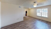 Located at 2080 Lobdell Blvd in Baton Rouge, Louisiana, this single-floor unit offers a well-designed layout with consistent wood-style flooring throughout. The open living and dining area is generously proportioned, bathed in natural light through blinded windows, and features ceiling fans and a textured ceiling. The space flows seamlessly toward the kitchen, which is visible from the living area and provides a practical, connected feel.

The galley-style kitchen is thoughtfully outfitted with warm honey-toned cabinetry, granite-look countertops, a stainless steel sink, and a full suite of black and stainless steel appliances including a refrigerator, range, microwave, and dishwasher. A centrally positioned window fills the kitchen with natural light.

The bedrooms continue the wood-style flooring and feature ceiling fans, natural light from windows, and access to closet space. The rooms offer a clean, neutral palette suited for a variety of furnishing styles.

The bathroom includes dark wood-style vinyl flooring, a tiled tub and shower surround with decorative accents, chrome fixtures, and a vanity with a stone-look countertop. The overall design of the unit maintains a cohesive, functional aesthetic throughout all areas.