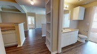 Located at 3131 SW 89th St in Oklahoma City, Oklahoma, this single-floor unit offers a well-organized layout with a variety of functional living spaces. The living area is finished with rich wood-look flooring and features crown molding, a textured ceiling, and a sliding glass door that opens to a private balcony, allowing natural light to fill the room. Adjacent to the living space, the kitchen is designed with an open peninsula countertop finished in a light stone pattern, white cabinetry with ample storage, a range with overhead ventilation, and track lighting above, creating a practical and bright cooking environment. A built-in shelving unit between the main living area and the bathroom area adds additional storage and visual interest. The bedrooms are carpeted for comfort, each featuring windows with blinds that bring in natural light, and one room includes a ceiling fan. The bathrooms are finished with wood-look flooring, white vanity cabinetry, light countertops, large mirrors, and shower-tub combinations. One bathroom benefits from direct exterior access, adding convenience. Overall, the unit presents a clean, neutral palette throughout with warm beige tones and white trim, offering a move-in ready living environment.