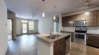 Located at 645 Old Hickory Blvd in Nashville, TN, this 2-bedroom, 2-bathroom residence offers a thoughtfully designed single-floor layout with modern finishes throughout. The open-concept kitchen and living area serves as the heart of the home, featuring rich dark wood cabinetry, a subway tile backsplash, stainless steel appliances, and a granite-topped center island with pendant lighting overhead — ideal for both cooking and entertaining. Hardwood-style flooring flows through the main living areas, complemented by a ceiling fan and a glass door that brings in natural light.

The two bedrooms are generously proportioned, each offering plush carpeting, ceiling fans, and windows with views of surrounding greenery. The primary bedroom connects to a well-sized en-suite bathroom featuring a granite vanity with dark wood cabinetry, a tiled shower, and hardwood-style flooring. A spacious walk-in closet with wire shelving provides ample storage. The second bathroom offers a full tub-shower combo with clean white subway tile. Both bedrooms include dedicated closets, enhancing overall storage. The unit's neutral color palette and contemporary design elements create a clean, welcoming ambiance throughout.