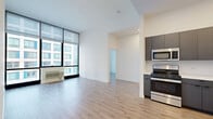 Located at 9 Homestead Pl in Jersey City, NJ, this modern 2-bedroom, 1-bathroom unit offers a thoughtfully designed layout with contemporary finishes throughout. Light wood-style flooring runs continuously across the space, complementing the clean white walls and creating a bright, cohesive aesthetic.

The open-concept living room and kitchen area serves as the heart of the unit. Floor-to-ceiling windows flood the living area with natural light and frame striking urban skyline views. The kitchen features sleek, dark gray cabinetry, white countertops, and a full suite of stainless steel appliances including a gas range, over-the-range microwave, and refrigerator.

Both bedrooms are well-proportioned and benefit from large windows with city views, continuing the light and airy feel of the unit. The second bedroom features an expansive floor-to-ceiling window wall, while the primary bedroom offers a wide panoramic view of the surrounding cityscape.

The bathroom is finished with large-format neutral tiles, a glass-enclosed shower, and a dark wood vanity with a white countertop. Additional conveniences include in-unit laundry and three closets, providing ample storage. A hallway connects the private areas of the unit efficiently, rounding out this well-appointed urban residence.