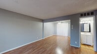 This two-story home features two bedrooms, one bathroom, and a thoughtfully arranged layout spread across two floors. Warm hardwood-style flooring and neutral grey walls flow consistently throughout, creating a cohesive and inviting atmosphere.

The main floor houses two living areas, offering flexibility for a dedicated sitting room and a separate dining or lounge space. The front living room benefits from a large window that fills the area with natural light, with a staircase conveniently positioned nearby. The kitchen is well-equipped with white cabinetry, granite-style countertops, and black appliances including a range, over-the-range microwave, and refrigerator.

Upstairs, both bedrooms are comfortable and well-lit, each featuring ceiling fans with light fixtures and windows that allow in natural light. The primary bedroom includes a closet and direct access to the shared bathroom. The second bedroom also features a built-in shelving unit, adding practical storage. Each bedroom benefits from its own closet space.

The full bathroom is finished with a white vanity, round mirror, tiled shower-tub combination, and hardwood-style flooring, maintaining the clean aesthetic found throughout the home. A hallway connects the upstairs rooms, completing the practical and straightforward layout of this well-maintained two-story residence.