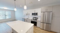 Located at 83 Pleasant Valley St in Methuen, MA, this thoughtfully designed one-bedroom, one-bathroom residence offers a comfortable and modern living experience across a single floor. The open-concept kitchen and dining area serves as the heart of the home, featuring sleek white cabinetry, a white subway tile backsplash, a full suite of stainless steel appliances including a refrigerator, range, microwave, and dishwasher, and a central island with a white quartz countertop illuminated by pendant lighting. Warm-toned hardwood-style flooring flows throughout the main living area, enhancing the bright and airy ambiance created by recessed lighting. The bedroom offers a cozy, well-proportioned retreat with plush carpeting, a large window with blinds that invites natural light, and direct access to a dedicated closet outfitted with wire shelving for organized storage. The bathroom is finished in a clean, contemporary style with a wide vanity, undermount sink, ample cabinet storage, and a large wall mirror with overhead lighting. Neutral walls and modern hardware throughout the residence contribute to a cohesive, move-in-ready aesthetic well-suited for comfortable everyday living.