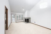 This single-floor residence offers a well-organized layout with a blend of comfort and modern finishes throughout. The living room is a standout space, featuring soaring vaulted ceilings, plush wall-to-wall carpeting, and a corner fireplace clad in tile — a practical and visually appealing focal point. A large window frames views of mature trees and greenery, filling the room with natural light and a sense of connection to the outdoors.

The kitchen is designed for functionality, featuring rich dark wood cabinetry, granite-look countertops, and stainless steel appliances including a range, over-the-range microwave, and refrigerator. A pass-through bar counter opens the kitchen to the living and dining area, which is anchored by a pendant light fixture and continues the open, airy feel.

A hallway with hardwood-style flooring connects the rooms, leading to two carpeted bedrooms, each with windows overlooking an exterior deck or wooded surroundings. The primary bathroom is equipped with a long vanity, generous mirror, and a walk-in glass-enclosed shower, while a secondary bathroom provides a vanity and toilet. Consistent dark wood trim and neutral wall tones create a cohesive aesthetic throughout the entire space.