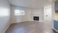 Located at 1672 Dover St in Lakewood, Colorado, this three-bedroom, one-bathroom unit offers a practical and efficiently organized single-floor layout. The living room serves as the heart of the space, featuring a corner fireplace with a clean white mantel, light gray luxury vinyl plank flooring, and a window that brings in natural light, creating a bright and welcoming atmosphere.

The kitchen is directly accessible from the living area and includes a peninsula with a light-toned countertop and distinctive blue cabinetry, providing both workspace and a visual focal point. White appliances, including a refrigerator, electric range, and microwave, are integrated into the layout alongside upper cabinetry for ample storage.

A carpeted hallway connects the three bedrooms and the shared bathroom. The bedrooms vary in size, with the primary bedroom offering the most generous proportions. Bedrooms feature neutral carpet, large windows for natural light, and clean white walls. One bedroom features LVP flooring. The bathroom includes a gray vanity with a stone-look countertop, a framed mirror, and wood-style flooring, offering a tidy and updated finish throughout.