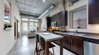 Located at 2838 Fremont Ave S in Minneapolis' vibrant Uptown neighborhood, this one-bedroom, one-bathroom loft delivers a striking industrial-chic aesthetic throughout its efficiently designed single-floor layout. The open-concept kitchen and living area serves as the heart of the space, showcasing soaring concrete ceilings with exposed silver ductwork and track lighting that lend an urban warehouse character. The well-appointed kitchen features rich dark wood cabinetry reaching nearly to the ceiling, stainless steel appliances including a range, microwave, dishwasher, and refrigerator, complemented by sleek countertops and a freestanding island with bar seating — ideal for casual dining and entertaining. Polished concrete floors flow through the main living area, where floor-to-ceiling windows and a glass door flood the space with abundant natural light and offer lush outdoor views. The bedroom provides a comfortable retreat with plush carpeting, generous window access, and three closets offering ample storage. The bathroom is clean and functional, featuring a tiled tub-shower combination, dark vanity cabinetry, and polished concrete flooring that ties back to the overall modern aesthetic. This loft combines bold architectural character with practical, well-considered design throughout.