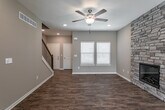 Located at 21322 W 65th St in Shawnee, Kansas, this three-floor home offers a well-designed layout with a variety of functional spaces across its levels. The main living area features warm wood-look flooring, neutral taupe walls, and a striking floor-to-ceiling stacked stone fireplace that serves as a focal point of the room. A ceiling fan with light kit provides comfort, while a staircase connects the floors. Natural light filters in through blinds-equipped windows throughout. The kitchen is outfitted with crisp white cabinetry, granite-look countertops, and a full suite of stainless steel appliances including a range, microwave, and dishwasher, complemented by wood-look flooring. A half bathroom on the main level includes a white vanity with granite-style countertop and matching hardware. Upper-level bedrooms are finished with plush carpeting, ceiling fans, and windows that bring in natural light, offering comfortable and quiet retreats. A hallway bathroom features a granite-topped white vanity and wood-look flooring. The unfinished basement spans a generous footprint across multiple rooms, complete with exposed wood framing, concrete walls, and mechanicals including a water heater, presenting excellent potential for future finishing and customization.