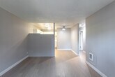 Located at 200 Button St in Santa Cruz, CA, this 2-bedroom, 1-bathroom unit offers a practical and well-organized single-floor layout. Light wood-style flooring runs throughout, complementing the neutral warm-gray walls and white trim found in every room. The combined kitchen and living area forms the heart of the unit, with the kitchen featuring white cabinetry, white countertops, and a full suite of white appliances including a refrigerator, electric range, and over-the-range microwave. A ceiling fan and wall heater provide year-round comfort in the living area, which receives natural light through sliding windows with views of lush greenery outside. The primary bedroom is a comfortable, well-proportioned room with a sliding window that brings in natural light and outdoor views of mature trees. The second bedroom also benefits from natural light and its own wall heater. A dedicated walk-in closet with built-in shelving and a dresser provides ample storage. The bathroom is clean and functional, featuring a white vanity with storage, a lighted mirror, and a shower/tub combination. Textured ceilings are present throughout, and a hallway connects all areas of the unit efficiently. Wall heaters in multiple rooms ensure consistent comfort year-round.