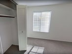 This 700 square foot apartment in South Bend, Indiana, offers a practical living space with three bedrooms and one bathroom. The single-story layout maximizes efficiency, with the primary bedroom boasting a generous 300 square feet. The modern kitchen features white cabinetry, stainless steel appliances, and a gas range, complemented by light wood-tone flooring. The bathroom showcases a contemporary vanity with a marble-like countertop and wooden floors. Throughout the apartment, neutral-toned carpeting and white walls create a bright, airy atmosphere. Large windows in the bedrooms and living area allow for ample natural light, while vertical blinds on sliding glass doors provide privacy and outdoor access. Built-in closets with louvered doors offer convenient storage solutions. The apartment's design emphasizes functionality and comfort, making efficient use of its compact footprint while providing separate spaces for sleeping, living, and dining.