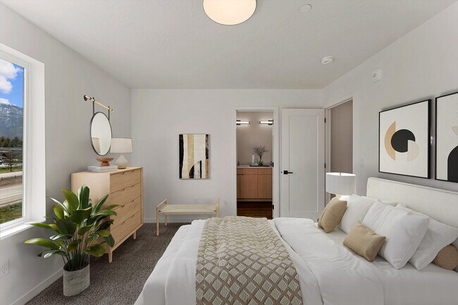 Dormitorio luminoso y acogedor con decoración moderna, que cuenta con una cómoda cama, elegantes obras de arte y una vista panorámica desde la ventana. - Coal Creek Townhomes