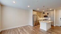Located at 721 Halifax St in Raleigh, NC, this single-floor residence offers a thoughtfully designed open-concept layout with contemporary finishes throughout. Wood-look luxury vinyl plank flooring flows seamlessly across the entire space, creating a warm and cohesive aesthetic.

The kitchen serves as the centerpiece of the home, featuring crisp white shaker-style cabinetry with matte black hardware, a classic white subway tile backsplash, and a full suite of stainless steel appliances including a range, microwave, and refrigerator. A central island with a clean white countertop provides additional prep space and is illuminated by sleek pendant lighting above. Ample cabinet storage, including a tall pantry-style cabinet, adds to the kitchen's practicality.

The living and bedroom areas are bright and airy, benefiting from large windows dressed with horizontal blinds that invite generous natural light and views of the surrounding neighborhood. Ceiling fans provide additional comfort in the bedrooms. Closet space is well-appointed, with open shelving visible in at least one walk-in-style closet.

The bathroom is a standout feature, showcasing a frameless glass walk-in shower adorned with large white square tiles and accented by matte black fixtures, including a rain showerhead. Light gray floor tiles complete the refined, modern look. Recessed lighting throughout the unit adds to its clean, polished ambiance.