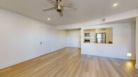 Located in Phoenix, AZ, this single-floor, 2-bedroom, 1-bathroom residence offers a thoughtfully designed layout with a bright, contemporary aesthetic throughout. Light wood-style flooring runs consistently across the entire space, contributing to a cohesive and airy feel.

The open-concept living area is generously proportioned, anchored by a ceiling fan with recessed lighting above. It flows seamlessly into the kitchen, which is separated by a half-wall pass-through with a built-in sink — an architectural detail that enhances connectivity while maintaining definition between spaces. The kitchen is well-appointed with white cabinetry, a white tile backsplash, gray countertops, and a full suite of stainless steel appliances including a refrigerator, electric range, and over-the-range microwave.

The spacious primary bedroom occupies roughly half the total floor area, offering ample room and a ceiling fan. The second bedroom is bright with a window fitted with vertical blinds and its own ceiling fan. Both bedrooms feature light, neutral walls and closet storage with sliding doors.

The bathroom is clean and functional, featuring a full tub-shower combination with brushed nickel fixtures. A hallway connects the rooms efficiently, completing this well-organized and move-in-ready home.