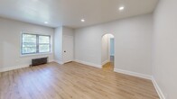Located at 601 W Cliveden St in Philadelphia's Mt. Airy neighborhood, this 2-bedroom, 2-bathroom single-floor residence offers a thoughtfully updated interior with a clean, modern aesthetic. Light wood luxury vinyl flooring runs throughout, complementing the crisp white walls and recessed lighting found in each room.

The living room is a bright, open space featuring a charming arched doorway, a window overlooking lush greenery, and a cast-iron radiator that adds a touch of classic character. The generously sized primary bedroom similarly features a radiator and natural light from a window with outdoor views.

The kitchen is well-appointed with white shaker-style cabinetry, stainless steel appliances including a gas range and refrigerator, a wall-mounted range hood, and a striking deep teal subway tile backsplash that adds bold visual interest. The same teal tile is carried into both bathrooms, where it lines the shower and tub surrounds, paired with matte black fixtures and white vanities for a cohesive, contemporary look. A dedicated closet provides additional storage.

Two hallways connect the rooms efficiently throughout the layout. The space is rounded out by recessed lighting, clean white trim, and a consistently updated finish palette that gives the entire unit a fresh, move-in-ready feel.