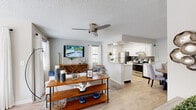 This single-story, one-bedroom, one-bathroom unit offers a thoughtfully designed layout that maximizes its compact footprint. The open-concept living, dining, and kitchen area forms the heart of the space, with light-toned hardwood-style flooring and a textured ceiling running throughout. The living room receives natural light from multiple windows dressed with white curtains, complemented by a ceiling fan overhead. A defined dining nook adjacent to the kitchen comfortably accommodates a four-seat table.

The galley-style kitchen features white cabinetry with modern hardware, granite-look countertops, a tile backsplash, and a full suite of stainless steel appliances, including a refrigerator, range, and dishwasher. A window at the end of the kitchen allows additional natural light.

The bedroom is carpeted and includes a ceiling fan, accent wall, and a dedicated walk-in closet with built-in shelving. The bathroom is finished with white cabinetry, a granite-top vanity, a large mirror, and a shower-tub combination. A hallway connects the private areas of the unit to the main living space, contributing to a clear and functional flow throughout.