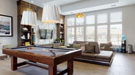 Located at 8332 Erickson Blvd in Littleton, Colorado, this single-floor community clubhouse offers a thoughtfully designed gathering space that blends modern aesthetics with warm, natural materials. The open-plan layout is anchored by a central game lounge, where a full-size hardwood pool table takes center stage beneath striking geometric pendant lights. Soaring tray ceilings and floor-to-ceiling windows flood the space with abundant natural light and provide views of the surrounding neighborhood. A built-in entertainment wall features a large flat-screen TV set against a distinctive reclaimed wood accent surround, complemented by open shelving and integrated cabinetry. The lounge seating area includes rounded upholstered chairs, a sculptural wood bowl coffee table, and green accent ottomans arranged atop a patterned area rug. A fully equipped kitchen and dining area showcases a stunning live-edge wood dining table paired with leather side chairs, dark wood cabinetry with open upper shelving, white quartz countertops, stainless steel appliances, and a wall-mounted TV — ideal for gatherings and events. Throughout, warm wood-toned flooring, curated décor, and layered lighting create a cohesive, welcoming ambiance suited for both social and casual use.