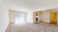 This single-floor residence offers a practical and comfortable layout across four distinct rooms. The living room is a generous, light-filled space anchored by sliding glass doors dressed with vertical blinds, allowing abundant natural light to pour in and providing access to an outdoor area. Soft wall-to-wall carpeting extends throughout the living room and bedroom, lending a warm, cozy ambiance. A ceiling fan overhead adds an additional functional detail to the space.

The kitchen is efficiently designed, featuring warm wood cabinetry, granite-style countertops, a stainless steel sink, and black appliances including a gas range and over-the-range microwave. Light hardwood-style flooring ties the kitchen together, giving it a clean, polished look.

The bedroom is spacious and bright, with a large sliding glass door that fills the room with natural light. It includes a built-in closet with rod and shelving, offering practical storage. The room's neutral carpeting and white walls provide a calm, restful atmosphere.

The bathroom is neatly appointed with a full tub-shower combo featuring white tile surround, tile flooring, and a vanity with granite-style countertops, maintaining a cohesive design aesthetic consistent with the rest of the home.