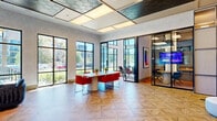 Located at 112 Bilby Road in Hackettstown, NJ, this generously sized fitness center offers a thoughtfully designed, single-floor layout that accommodates a full range of workout activities. The main workout hall is defined by a dramatic vaulted ceiling adorned with exposed natural wood beams, wood-paneled cladding, and integrated linear LED lighting that creates a bright, energizing atmosphere. Skylights and expansive floor-to-ceiling windows along multiple walls flood the space with natural light while providing open views of the surrounding outdoor amenities.

The main floor is finished with durable rubber sport tile flooring throughout and is equipped with an extensive array of strength training stations, including cable machines, multi-functional racks, free weight benches, and a full dumbbell rack displayed along a mirrored wall. Cardio equipment — including treadmills, ellipticals, and stationary bikes — is arranged to take advantage of the outdoor views. A dedicated functional training area features a heavy bag, TRX suspension system, rowing machine, and stability equipment, complemented by a wall-mounted television. A separate glass-enclosed studio area provides additional space for group or individual workouts. The overall ambiance is modern, clean, and professionally appointed, making this facility a comprehensive destination for fitness and wellness.