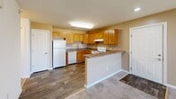Located at Friendship Village in Harrington, Delaware, this one-bedroom, one-bathroom residence offers a well-organized single-floor layout designed for comfortable everyday living. The open-concept kitchen and living room area serves as the heart of the home, featuring warm honey-toned oak cabinetry, laminate countertops, and white appliances including a range, dishwasher, and refrigerator. A peninsula counter provides a natural transition between the kitchen and the carpeted living area, which benefits from a sliding glass door fitted with vertical blinds that allows an abundance of natural light to fill the space. The living area is generously proportioned, offering ample room for a variety of furniture arrangements. The spacious primary bedroom is finished with plush carpet and features a large window that brings in natural light and views of the surrounding community. A dedicated closet provides convenient storage. The full bathroom is cleanly appointed with a single-sink vanity with a light stone-style countertop, oak cabinetry, a tub/shower combination, and wood-look flooring. A hallway connects the main living spaces, completing this practical and cohesive floor plan.