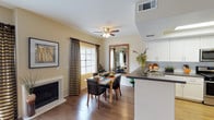 This two-story residence located on Summit Vue Drive in the Woodland Hills area of Los Angeles offers a well-designed layout spread across two levels. The main living area is an open, light-filled space anchored by a fireplace and framed by multiple large windows with sliding glass door access, allowing generous natural light to flow through. Wood-look flooring extends through the living and dining areas, which connect seamlessly to the kitchen. A ceiling fan overhead adds to the comfortable ambiance of the combined living and dining space.

The kitchen is equipped with white shaker-style cabinetry, dark countertops, stainless steel appliances including a gas range and microwave, and a double basin sink, all set beneath a tray ceiling detail. A breakfast bar creates a natural transition between the kitchen and dining area.

The upper level features bedrooms with vaulted ceilings, carpet flooring, and ample closet space. The primary bedroom is notably spacious with dramatic ceiling height. Additional bedrooms are well-proportioned and comfortable. Bathrooms include updated vanities with dark countertops, wood-look flooring, and clean white fixtures, with at least one full bath featuring a shower-tub combination.