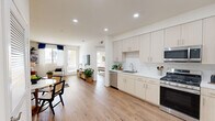 This two-story, 2-bedroom, 3-bathroom home is thoughtfully designed with a clean, modern aesthetic and functional layout across two well-proportioned floors. The main level features an open-concept living and kitchen area, where warm hardwood-style flooring flows seamlessly throughout. The kitchen is fully equipped with stainless steel appliances—including a French door refrigerator, gas range, microwave, and dishwasher—complemented by light wood cabinetry, white countertops, and a subway tile backsplash. A window above the sink brings in natural light, while recessed lighting illuminates the entire space. The spacious living room connects directly to the kitchen and opens to a door leading to a private outdoor area, filling the room with abundant natural light. A hallway on the main level provides convenient storage with louvered closet doors. The bathrooms are finished with light wood vanities, white countertops, and tile flooring; one features an elegant marble-surround tub and shower combination. Upstairs, both bedrooms are bright and airy, each offering access to a private outdoor balcony, generous closet space—including mirrored sliding doors in the primary bedroom—and large windows with vertical blinds. A staircase connects both levels, completing this well-designed, move-in-ready home.