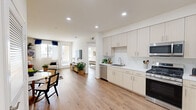 This two-story, 2-bedroom, 3-bathroom home is thoughtfully designed with a clean, modern aesthetic and functional layout across two well-proportioned floors. The main level features an open-concept living and kitchen area, where warm hardwood-style flooring flows seamlessly throughout. The kitchen is fully equipped with stainless steel appliances—including a French door refrigerator, gas range, microwave, and dishwasher—complemented by light wood cabinetry, white countertops, and a subway tile backsplash. A window above the sink brings in natural light, while recessed lighting illuminates the entire space. The spacious living room connects directly to the kitchen and opens to a door leading to a private outdoor area, filling the room with abundant natural light. A hallway on the main level provides convenient storage with louvered closet doors. The bathrooms are finished with light wood vanities, white countertops, and tile flooring; one features an elegant marble-surround tub and shower combination. Upstairs, both bedrooms are bright and airy, each offering access to a private outdoor balcony, generous closet space—including mirrored sliding doors in the primary bedroom—and large windows with vertical blinds. A staircase connects both levels, completing this well-designed, move-in-ready home.