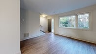 This thoughtfully designed two-story home in Atlanta's sought-after Virginia-Highland area offers a clean, modern aesthetic throughout. The main floor features an open-concept living area with light hardwood-style flooring, neutral walls, and natural light streaming through large windows with views of surrounding greenery. The contemporary kitchen is equipped with stainless steel appliances—including a French door refrigerator, dishwasher, and range—complemented by white cabinetry, a subway tile backsplash, a peninsula with pendant lighting, and track lighting overhead. A utility room with a washer and dryer is conveniently located adjacent to the kitchen. A staircase with dark-toned steps connects both floors. The upper level houses the spacious primary bedroom, which features a ceiling fan, hardwood-style flooring, and a wide window that fills the room with natural light and outdoor views. Two well-appointed bathrooms serve the home, one featuring a floating wood-toned vanity with a vessel sink, modern pendant lighting, and a large mirror, and the other with a full soaking tub surrounded by large-format tile. Two closets provide ample storage throughout. The overall ambiance is bright, clean, and contemporary.