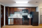 Located at 930 N Henry St in Alexandria, Virginia, this two-bedroom, two-bathroom residence offers a well-designed single-level layout that maximizes functionality. The open-concept kitchen and living area serves as the heart of the home, featuring rich dark-wood cabinetry, granite countertops, a subway tile backsplash, and black appliances including a refrigerator, electric range, microwave, and dishwasher. Wood-style plank flooring runs throughout, adding warmth and visual continuity across the space. Both bedrooms are comfortably sized, with the primary bedroom offering a generous footprint. Each room benefits from large windows that invite natural light and provide views of the surrounding neighborhood. The two full bathrooms are finished with clean white subway tile surrounding soaking tub-shower combinations, complemented by brushed nickel fixtures and tile flooring. Three closets provide ample storage throughout the unit, and a dedicated laundry area adds everyday convenience. The neutral color palette and modern finishes create a cohesive, move-in-ready aesthetic. The overall layout flows efficiently, making excellent use of the available square footage in this Alexandria address.