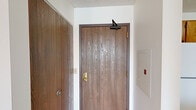 This one-bedroom, one-bathroom unit is located on the second floor in Saint Paul, Minnesota, offering a practical and functional layout. Upon entry, a wood-paneled door with an automatic closer opens into a hallway that connects seamlessly to the main living areas. The combined kitchen and living room provides an open, efficient use of space. The kitchen is equipped with warm oak cabinetry extending to the ceiling, white appliances including a coil-burner electric range and refrigerator, a double sink, and light-toned laminate countertops, all set atop vinyl tile flooring. The living area features neutral carpeting and baseboard heating throughout. A standout feature is the angled bay window in the living room, which invites natural light and frames outdoor views of surrounding trees. The bedroom is a comfortable size, with plush carpeting, a window overlooking the exterior, baseboard heating, and a closet with a sliding wood-panel door. The bathroom is well-appointed with a walk-in shower equipped with grab bars and a handheld showerhead, a wood-toned vanity with a single sink, a large mirror, and durable tile flooring. Neutral tones and practical finishes give the unit a clean, move-in-ready appeal.