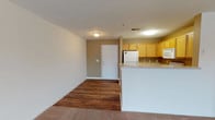 This well-appointed 2-bedroom, 2-bathroom single-floor residence offers a comfortable and practical layout designed for everyday living. The open-concept living and dining area features rich hardwood-style flooring that flows seamlessly into the kitchen, creating a cohesive and inviting common space. The kitchen is fully equipped with warm honey-toned cabinetry, a full suite of white appliances including a refrigerator, electric range, over-the-range microwave, and dishwasher, all complemented by ample counter space and a peninsula that separates the kitchen from the living area. The spacious living room is bathed in natural light through large windows and transitions into soft carpeting toward the bedroom wing. Both bedrooms are generously sized with plush carpet, large windows with blinds, and ceiling fans for added comfort. The primary bedroom features a walk-in closet with wire shelving for storage. The second bedroom includes its own closet as well. Each full bathroom is outfitted with a tub-shower combo, wood-tone vanity cabinetry, and hardwood-style flooring. Textured ceilings and neutral wall tones throughout lend a clean, understated aesthetic to the entire residence.