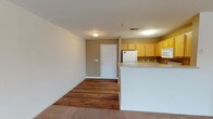 This well-appointed 2-bedroom, 2-bathroom single-floor residence offers a comfortable and practical layout designed for everyday living. The open-concept living and dining area features rich hardwood-style flooring that flows seamlessly into the kitchen, creating a cohesive and inviting common space. The kitchen is fully equipped with warm honey-toned cabinetry, a full suite of white appliances including a refrigerator, electric range, over-the-range microwave, and dishwasher, all complemented by ample counter space and a peninsula that separates the kitchen from the living area. The spacious living room is bathed in natural light through large windows and transitions into soft carpeting toward the bedroom wing. Both bedrooms are generously sized with plush carpet, large windows with blinds, and ceiling fans for added comfort. The primary bedroom features a walk-in closet with wire shelving for storage. The second bedroom includes its own closet as well. Each full bathroom is outfitted with a tub-shower combo, wood-tone vanity cabinetry, and hardwood-style flooring. Textured ceilings and neutral wall tones throughout lend a clean, understated aesthetic to the entire residence.