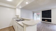 Located at 444 S Kingsley Dr in the Koreatown neighborhood of Los Angeles, this efficiently designed single-floor unit makes the most of its compact footprint. The open-concept kitchen and living area form the heart of the space, featuring warm wood-look flooring that runs throughout. The kitchen is outfitted with white cabinetry, granite-style countertops, a double-basin sink, and a white electric range. A peninsula counter extends into the living area, creating a natural divide between cooking and lounging spaces while maintaining an open, airy feel. Recessed lighting with a tray ceiling detail above the kitchen adds architectural interest.

The living area is bright and welcoming, highlighted by a dramatic floor-to-ceiling black stone fireplace that serves as a striking focal point. Sliding glass doors flood the room with natural light and provide outdoor access, while an additional window contributes to the sun-filled ambiance. A textured ceiling adds subtle character throughout.

A hallway connects to a well-appointed bathroom featuring wood-look flooring, a wide granite-style vanity with under-sink storage, a large wall mirror, and a tub-shower combination with sliding glass doors. A dedicated closet and entryway hallway complete the layout, offering practical storage within a streamlined, functional floor plan.