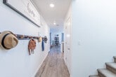 This two-story home offers a thoughtfully designed layout with modern finishes and a bright, neutral palette carried consistently throughout. Light wood-look flooring runs across the main level, complementing the crisp white walls and recessed lighting that keep the interior feeling open and airy.

The kitchen is outfitted with white shaker-style cabinetry, quartz countertops, a stainless steel sink, and a full suite of stainless steel appliances, including a range, over-the-range microwave, and refrigerator. Adjacent to the kitchen, the dining area features large windows with wood-slat blinds and elegant drapery, allowing ample natural light to fill the space. The living room continues the bright aesthetic with oversized windows overlooking the fenced backyard.

A dedicated flex room on the main level, complete with a window and natural light, is well-suited as a home office or study. A powder bathroom with a pedestal sink and oval mirror serves guests on this floor. Sliding glass doors lead to a private patio and fenced backyard, ideal for outdoor entertaining.

Upstairs, the primary bedroom is spacious and sun-filled, featuring multiple windows and light wood flooring. Its en-suite bathroom includes a dual-sink vanity with quartz countertops, white cabinetry, and a shower-tub combination. A carpeted staircase with a skylight above connects both floors, enhancing the home's sense of vertical openness.