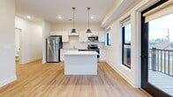 This contemporary 770 square foot apartment offers a well-designed living space with two bedrooms and two bathrooms. The unit features a thoughtful layout that maximizes functionality within its compact footprint. Upon entry, a hallway leads to the various rooms, creating a sense of privacy and separation.

The heart of the home is the open-concept kitchen, which boasts white cabinetry, stainless steel appliances, and a central island. Two pendant lights hang above the island, adding both style and task lighting. The kitchen flows seamlessly into the living area, which is adorned with warm wood-look flooring, creating an inviting atmosphere for relaxation and entertainment.

Both bedrooms are carpeted for comfort and feature large windows that flood the spaces with natural light. The primary bedroom, measuring 110 square feet, provides a cozy retreat. The bathrooms are designed with clean lines and modern fixtures, including a combination bathtub and shower in at least one of them.

Throughout the apartment, neutral-toned walls and ample windows create a bright and airy ambiance. The unit also includes two closets for storage. The overall design aesthetic is minimalist and contemporary, with a focus on functionality and comfort in a compact urban living space.