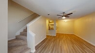 This two-floor residence offers a thoughtfully designed layout spread across two levels. The main floor features an open living area with warm-toned luxury vinyl plank flooring and a ceiling fan with integrated lighting. A staircase with carpeted treads and clean white trim leads to the upper level. The kitchen is accessible via a pass-through counter and is outfitted with white cabinetry, dark countertops, a subway tile backsplash, stainless steel appliances including a refrigerator, microwave, and range, as well as a single-basin sink — all arranged in a functional galley-style configuration.

Upstairs, the bedrooms are generously proportioned, each featuring light vinyl plank flooring, ceiling fans, and large windows or sliding glass doors dressed with vertical blinds that allow ample natural light and outdoor views. The bathrooms are clean and functional, equipped with white shaker-style vanity cabinetry, dark-edged countertops with brushed nickel hardware, and full tub-shower combinations with tiled surrounds. Textured ceilings are present throughout the home, adding a subtle architectural detail. The overall aesthetic is neutral and move-in ready, with a light, airy ambiance supported by consistent flooring and a cohesive color palette.