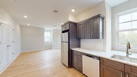 Located at 329 Totowa Rd in Totowa, New Jersey, this thoughtfully updated single-floor unit offers a clean, modern aesthetic throughout. The kitchen is a standout feature, showcasing rich dark-toned shaker-style cabinetry, crisp white countertops, a subway tile backsplash, and a full suite of stainless steel appliances including a refrigerator, gas range, microwave, and dishwasher. Natural light filters in through a window above the sink, and light hardwood flooring flows seamlessly throughout the entire unit, creating a warm and cohesive feel. The living areas are bright and open, with recessed lighting and neutral wall tones that complement the airy atmosphere. Bedrooms feature angled ceilings that add architectural character, along with windows that bring in natural light and views of the surrounding greenery. The unit includes two bathrooms: one with a gray shaker-style vanity, built-in open shelving, tile flooring, and a glass-enclosed shower, and another featuring a distinctive pentagonal frameless glass shower enclosure with white subway tile and a blue vanity. A dedicated in-unit laundry closet with a side-by-side washer and dryer adds everyday convenience to this well-appointed space.