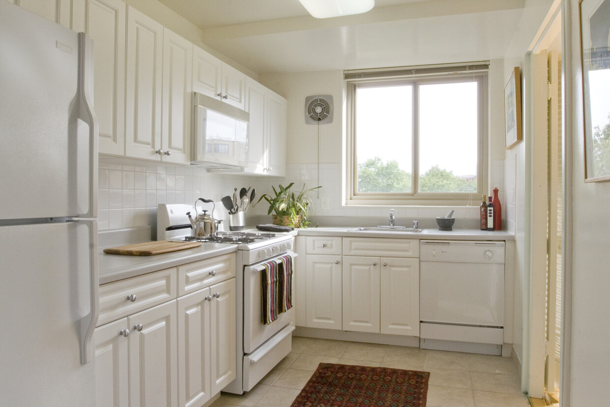 Kitchen with white cabinetry, white countertops, white appliances, tile backsplash and tile flooring - Avalon The Albemarle