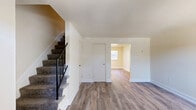 Located in Severn, MD, this two-bedroom, one-bathroom two-story home offers a functional and well-appointed layout spread across two floors. The main level features a bright living area with wood-look vinyl plank flooring, large windows with vertical blinds, and a front entry door that allows natural light to fill the space. The kitchen is a standout feature, equipped with dark espresso cabinetry, granite countertops, a gas range, dishwasher, microwave, and a full-size refrigerator. A stacked Whirlpool washer and dryer unit is conveniently integrated into the kitchen area, with a sliding glass door nearby providing outdoor access and additional natural light.

The upper floor houses both bedrooms and the full bathroom. The spacious primary bedroom features rich wood-tone vinyl plank flooring and a natural light-filled window with outdoor views. The second bedroom includes dual sliding-door closets, offering generous storage. Both bedrooms are finished with neutral tones and clean white trim throughout. The shared full bathroom features classic white subway tile wainscoting, a tub-shower combination, tile flooring, and a window for natural ventilation. A carpeted hallway connects the upstairs rooms, completing this efficiently designed home.