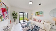 Located in Hialeah, FL, this well-appointed one-bedroom, two-bathroom unit offers a clean, modern aesthetic defined by gleaming marble-look porcelain tile floors that run throughout the entire space. The open-concept living and dining area is bright and airy, with large sliding glass doors that flood the interior with natural light and provide direct access to a private patio overlooking a lush green lawn with palm trees and serene water views beyond the iron fence. The kitchen is thoughtfully designed with flat-front taupe cabinetry, white quartz countertops, a gold-tone undermount sink, and stainless steel appliances, including a range, microwave, and dishwasher. A hallway connects the main living areas to the spacious primary bedroom, which benefits from generous closet space — with a total of four closets throughout the unit. Both bathrooms are finished with marble-look tile, featuring sleek vanities with white countertops. The second bathroom includes a full soaking tub with a striking floor-to-ceiling marble-tile surround. A dedicated utility room and hallway add to the practical layout. The overall ambiance is light, clean, and contemporary, making excellent use of the available space.