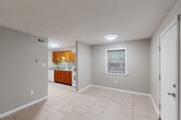 Located at 2600 Houma Blvd in Metairie, Louisiana, this efficient one-bedroom, one-bathroom unit offers a thoughtfully designed single-floor layout. The open living area features neutral gray walls, light ceramic tile flooring, and a textured ceiling, creating a clean and understated aesthetic. Natural light filters in through a window overlooking the exterior, adding brightness to the space.

The kitchen is a standout feature, showcasing rich warm-toned wood cabinetry, granite-look countertops, a stainless steel sink, and a mosaic tile backsplash that adds a decorative accent. White appliances, including a range, microwave, and dishwasher, complete the functional setup.

The bedroom offers a comfortable, well-lit retreat with wood-look vinyl flooring, two windows that invite natural light, and a ceiling fan with a light fixture overhead. Multiple doorways connect the bedroom to the bathroom and a utility closet, enhancing the unit's practicality.

The bathroom is neatly appointed with a vessel sink set atop a wood vanity with a granite countertop, a framed mirror, and a tub-shower combination with a curtain. The consistent use of warm wood tones and neutral gray walls throughout ties the unit together with a cohesive, polished look.