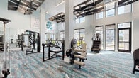 Located in Longwood, Florida, this fitness center is a thoughtfully designed, single-floor facility offering a generous and open workout environment. The space immediately impresses with its dramatic double-height ceilings adorned with striking geometric, angular ceiling fixtures that add a bold, contemporary aesthetic throughout.

Large floor-to-ceiling windows and glass doors line the perimeter, flooding the interior with natural light and providing views of the outdoor surroundings. The flooring features a vibrant, multi-toned patterned carpet in teal, gray, and brown tones that adds energy and visual interest underfoot.

The facility is comprehensively equipped for a full-body workout, offering a wide array of strength training machines, a dedicated free weights section with a full dumbbell rack and benches, cable machines, and functional training equipment. The cardio section includes treadmills, ellipticals, a stair climber, and a stationary bike, all positioned to take advantage of the natural light from the windows.

Full-length mirrors along the walls enhance the sense of space and support form-focused training. Motivational wall graphics — including phrases like "You Can Do Hard Things," "You're Doing Great," and "Keep Going, Keep Growing" — contribute to an upbeat and encouraging atmosphere. Glass-panel doors lead to adjacent rooms, adding connectivity to the broader facility.