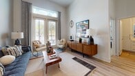 Located at 921 N Central Ave in Tampa, FL, this single-floor residence showcases a thoughtfully designed interior with modern finishes and a cohesive mid-century modern aesthetic throughout. The open-concept kitchen is a standout feature, boasting a striking two-tone design with navy blue lower cabinetry and crisp white upper cabinets, complemented by a textured tile backsplash, white quartz countertops, stainless steel appliances, and a central island with pendant lighting. A built-in mudroom area with open shelving adds both function and charm near the kitchen. The living room impresses with soaring ceilings and tall French doors that flood the space with natural light and provide access to a private balcony with outdoor views. Light wood-style flooring flows throughout the main living areas, enhancing the bright and airy ambiance. The bedroom features soft carpet, generous natural light from large windows, and high ceilings that reinforce the sense of spaciousness. The bathroom is well-appointed with white shaker cabinetry, brushed gold hardware, a glass-enclosed shower, and direct access to a walk-in closet with built-in shelving. Overall, the residence exudes a warm, contemporary character with carefully curated design details throughout.