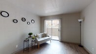 Located along IH-35 S in Austin, TX, this single-floor unit offers a thoughtfully designed layout that maximizes functionality and comfort. The living area features wood-style flooring and neutral-toned walls that create a bright, open atmosphere. A sliding glass door with vertical blinds leads to a private balcony, allowing natural light to fill the space and providing views of the surrounding exterior. The layout connects seamlessly to a dining nook equipped with a ceiling fan, visible through a pass-through opening that links the living area to the kitchen.

The galley-style kitchen is outfitted with dark cabinetry, granite-look countertops, a stainless steel refrigerator, an electric range, and a dishwasher — offering an efficient and well-equipped cooking space. Light wood-style flooring continues throughout, maintaining a cohesive aesthetic.

The bedroom is a comfortable retreat featuring wood-style flooring, a ceiling fan, and a window dressed with layered curtains that allow for adjustable natural light. The bathroom includes full tile surround in the shower/tub area, a dark vanity with a granite-look countertop, and wood-style flooring, delivering a clean and practical finish throughout.