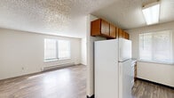 This single-floor unit at 5813 N Garrett St in Garden City, Idaho, offers a straightforward and functional layout across several distinct living areas. The living space features wood-look hard-surface flooring that extends through the main areas, with neutral white walls and a textured popcorn ceiling throughout. A wall-mounted air conditioning unit and baseboard heating provide year-round climate control, while windows fitted with horizontal blinds allow natural light to filter in.

The galley-style kitchen is well-equipped with warm wood-toned cabinetry lining both walls, offering ample upper and lower storage. White appliances, including a refrigerator and dishwasher, are complemented by light countertops, a double basin sink, and a window that brings in additional natural light. The kitchen opens toward the main living area, creating a connected feel between the two spaces.

The bedrooms feature plush carpeting and are served by baseboard heaters and windows. One bedroom includes a ceiling fan with integrated lighting, while another offers a sliding-door closet with double hanging rods for generous storage. The bathroom includes a tub/shower combination with a towel bar. Overall, the unit presents a clean, practical living environment suited for everyday comfort.