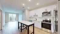 Located at 7220 Midlothian Turnpike in Richmond, VA, this well-designed 2-bedroom, 2-bathroom residence offers a thoughtful single-floor layout with a clean, contemporary aesthetic. The open-concept kitchen and living area serves as the heart of the home, featuring white shaker cabinetry with matte black hardware, a classic subway tile backsplash, white quartz countertops, and a full suite of stainless steel appliances including a French door refrigerator, range, microwave, and dishwasher. Light wood-style flooring flows throughout the main living areas, enhancing the bright, airy atmosphere. Sliding glass doors in the living area open to a private balcony with metal railing, offering views of the surrounding community. The two bedrooms are carpeted for comfort, with the primary bedroom featuring a ceiling fan and natural light from a window. Both bathrooms are finished with wood-look flooring, white vanities, matte black fixtures, and tiled tub-shower combinations. Additional conveniences include a dedicated laundry area, a utility room, and generous closet storage with five closets throughout. The overall ambiance is modern, clean, and move-in ready.