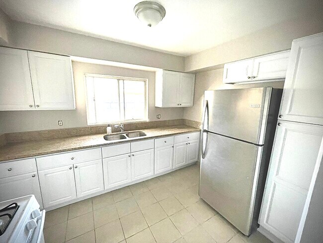 Amplia área de cocina con refrigeradores de acero inoxidable y mucho espacio de preparación. - 3851 Coco Ave